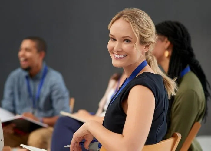 Smiling professional wearing a lanyard at a government leadership training workshop with engaged colleagues in the background